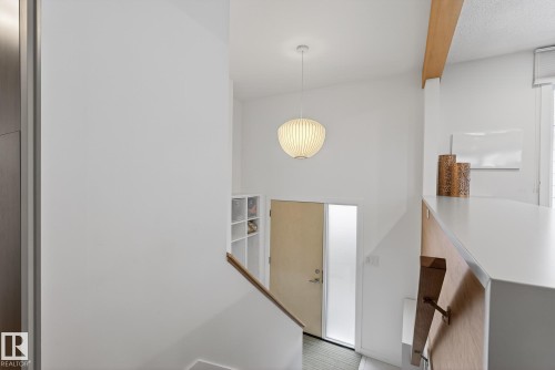 Entryway featuring a light wood door with an opaque glass insert and a contemporary hanging light fixture - 9736 78 Avenue, Edmonton, AB - Indoor Photo Showing Other Room