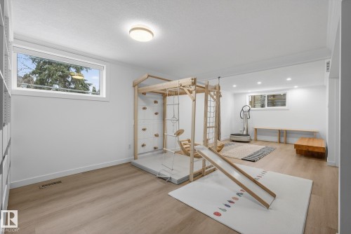 Spacious room featuring light wood flooring, white walls, and recessed lighting, with two windows providing natural light - 9736 78 Avenue, Edmonton, AB - Indoor