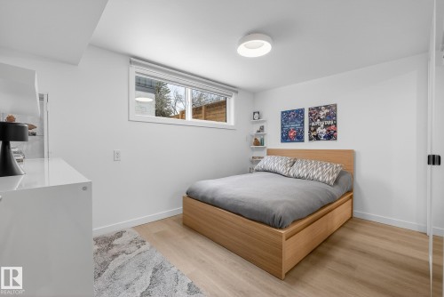 This room features light wood flooring, white walls, and a modern ceiling light fixture - 9736 78 Avenue, Edmonton, AB - Indoor Photo Showing Bedroom