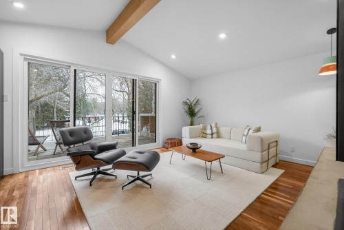 The living area features hardwood floors and a vaulted ceiling with an exposed wood beam - 9736 78 Avenue, Edmonton, AB - Indoor Photo Showing Living Room