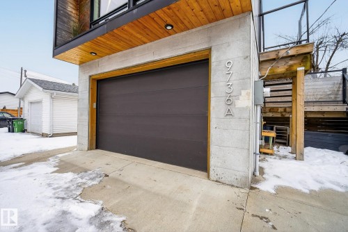 This property features an attached garage with a dark-colored garage door and concrete exterior - 9736 78 Avenue, Edmonton, AB - Outdoor With Exterior