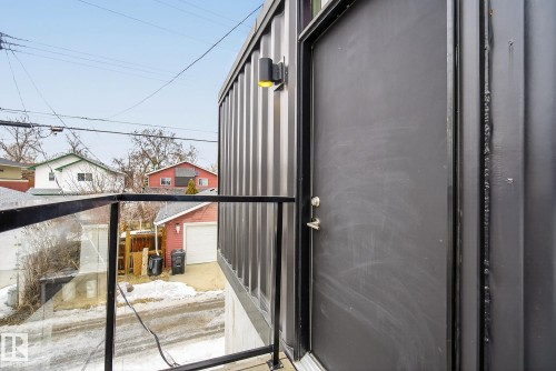 Exterior view featuring a sleek, dark-colored door and a contemporary metal facade with an integrated outdoor light - 9736 78 Avenue, Edmonton, AB - 