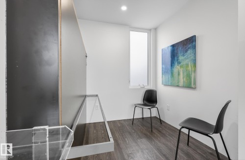 Room featuring white walls, dark flooring, and a tall window providing natural light - 9736 78 Avenue, Edmonton, AB - Indoor