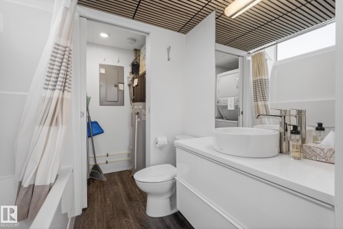 This bathroom features a white vanity with a vessel sink, a toilet, and a bathtub with a shower curtain - 9736 78 Avenue, Edmonton, AB - Indoor Photo Showing Bathroom