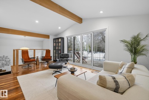 The living area features a vaulted ceiling with exposed wooden beams, hardwood flooring, and sliding glass doors that open to the exterior - 9736 78 Avenue, Edmonton, AB - Indoor Photo Showing Living Room