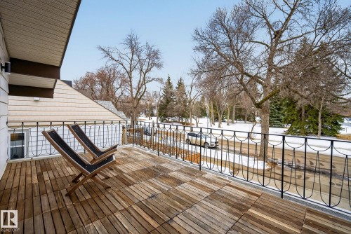 The property features a balcony with wooden deck flooring and a decorative metal railing, offering views of the surrounding neighborhood with mature trees - 9736 78 Avenue, Edmonton, AB - Outdoor With Exterior