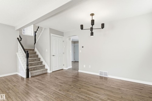 Expansive interior space featuring wood-finish flooring and a modern ceiling fixture - 8730 92A Avenue, Edmonton, AB - Indoor Photo Showing Other Room