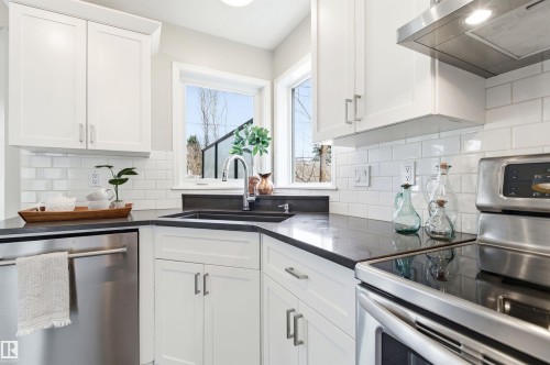 Modern kitchen featuring white shaker cabinetry, dark countertops, a stainless steel dishwasher, a stainless steel range with a smooth cooktop, and a subway tile backsplash - 8730 92A Avenue, Edmonton, AB - Indoor Photo Showing Kitchen With Upgraded Kitchen