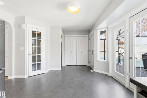 Spacious interior featuring grey tile flooring, white baseboards, and light grey walls - 8730 92A Avenue, Edmonton, AB - Indoor Photo Showing Other Room