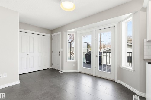 Spacious room featuring gray tile flooring, white baseboards, and a contemporary flush mount ceiling light - 8730 92A Avenue, Edmonton, AB - Indoor Photo Showing Other Room