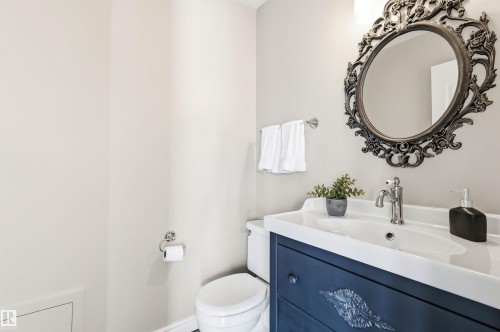 Vanity with an integrated white sink, chrome faucet, and a dark blue cabinet featuring decorative hardware - 8730 92A Avenue, Edmonton, AB - Indoor Photo Showing Bathroom