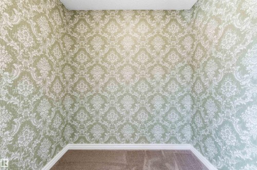 Room featuring light green and white damask-patterned wallpaper, white baseboards, and carpet flooring - 8730 92A Avenue, Edmonton, AB - 