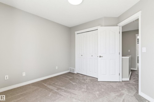 Neutral gray wall paint, white trim, and a textured gray carpet define this room - 8730 92A Avenue, Edmonton, AB - Indoor Photo Showing Other Room