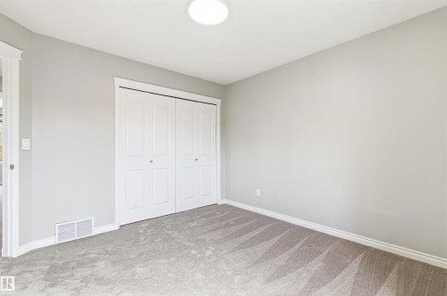 Neutral-toned room featuring a flush-mount ceiling light, light gray walls, a built-in bi-fold closet, and gray carpet flooring - 8730 92A Avenue, Edmonton, AB - Indoor Photo Showing Other Room