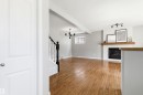 Open-concept living space featuring wood-finish flooring, a white-painted fireplace with a wood mantle, and a modern chandelier - 8730 92A Avenue, Edmonton, AB  - Indoor With Fireplace 