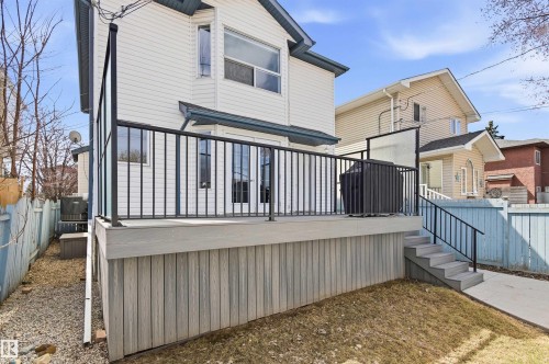 Rear exterior featuring a composite deck with black metal railings, leading to a concrete pathway - 8730 92A Avenue, Edmonton, AB - Outdoor With Exterior