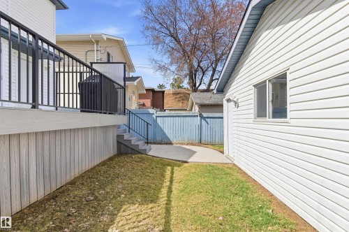 Rear yard featuring a white vinyl-sided structure, a concrete patio, and a light-colored wooden fence - 8730 92A Avenue, Edmonton, AB - Outdoor With Exterior