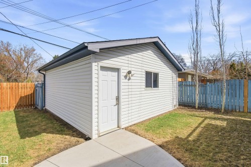 Detached white vinyl-sided structure featuring a single-panel door, small window, and dark gray shingle roof - 8730 92A Avenue, Edmonton, AB - Outdoor With Exterior