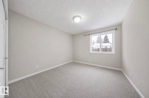 Spacious room featuring neutral carpeting, light gray wall paint, and white trim - 103 12110 119 Ave, Edmonton, AB - Indoor Photo Showing Other Room