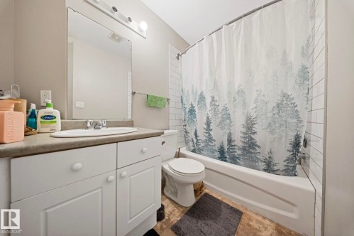 Bathroom featuring a white vanity with panel-front cabinetry, a single basin sink, and a large mirror - 103 12110 119 Ave, Edmonton, AB - Indoor Photo Showing Bathroom