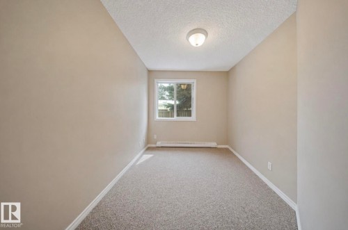 Neutral-toned room featuring a single window, textured ceiling, flush-mount ceiling light, and wall-to-wall carpeting - 103 12110 119 Ave, Edmonton, AB - Indoor Photo Showing Other Room