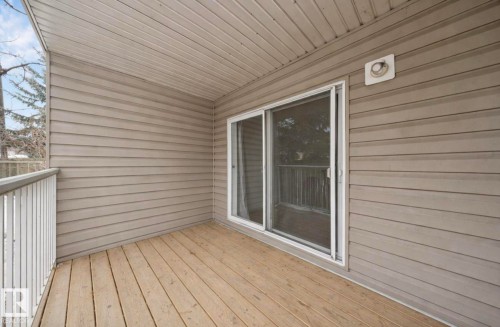 Covered exterior balcony with wood-finish decking, horizontal siding, and white railing - 103 12110 119 Ave, Edmonton, AB - Outdoor With Deck Patio Veranda With Exterior