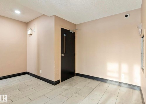 Interior room featuring light-toned walls and contrasting dark baseboards - 103 12110 119 Ave, Edmonton, AB - Indoor Photo Showing Other Room