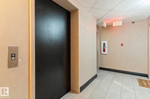 Elevator access featuring a large black door and a call button - 103 12110 119 Ave, Edmonton, AB - Indoor