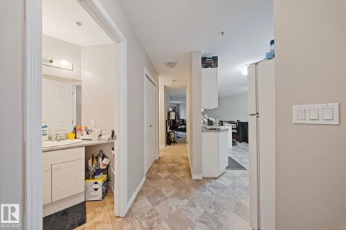 Bathroom vanity with a single basin sink, wall-mounted light fixture, and enclosed cabinetry - 103 12110 119 Ave, Edmonton, AB - Indoor