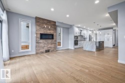 Open-concept living area featuring light wood-finish flooring, a built-in linear fireplace with a textured wood-look accent wall, and recessed lighting - 