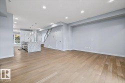 Open-concept living space with light wood-finish flooring, recessed ceiling lighting, and a kitchen island featuring a waterfall countertop - 