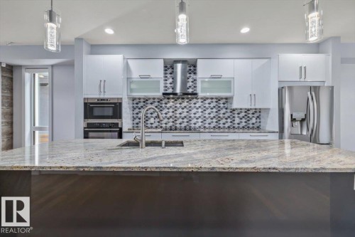 Kitchen featuring a large island with a stone countertop, an undermount sink, and a gooseneck faucet - 8706 88 Avenue, Edmonton, AB - Indoor Photo Showing Kitchen With Upgraded Kitchen