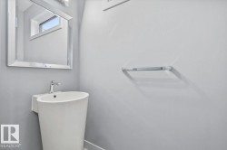 Pedestal sink with a single-handle chrome faucet, rectangular framed mirror, light gray wall paint, and a chrome towel bar - 