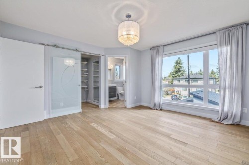 Light wood-finish flooring complements the wide picture window - 8706 88 Avenue, Edmonton, AB - Indoor