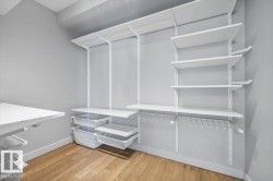 Customizable closet system with wood-finish flooring, white shelving, hanging storage, and pull-out storage bins - 