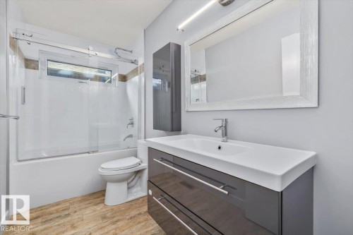Bathroom featuring a vanity with an integrated sink, a wall-mounted medicine cabinet, and a framed mirror - 8706 88 Avenue, Edmonton, AB - Indoor Photo Showing Bathroom