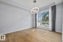 Spacious room featuring wood-finish flooring, a large multi-pane window, and a contemporary chandelier - 8706 88 Avenue, Edmonton, AB  - Indoor Photo Showing Other Room 