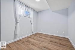 Room with wood-finish flooring, light grey painted walls, and white baseboards - 