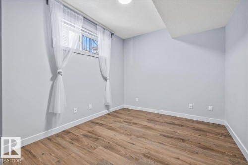 Room with wood-finish flooring, light grey painted walls, and white baseboards - 8706 88 Avenue, Edmonton, AB - Indoor Photo Showing Other Room