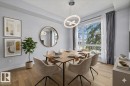 Bright dining area featuring a contemporary chandelier, wood-finish flooring, and a large window - 8706 88 Avenue, Edmonton, AB  - Indoor Photo Showing Dining Room 