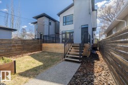 Rear exterior featuring a raised wooden deck with black railings, a gravel pathway, and horizontal slatted fencing - 