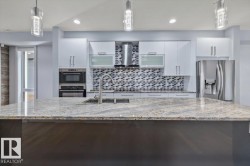 Kitchen featuring a large island with a stone countertop, an undermount sink, and a gooseneck faucet - 