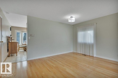 Spacious room featuring wood-finish flooring, light grey walls, and a recessed window with vertical blinds - 18227 76 Avenue, Edmonton, AB - Indoor Photo Showing Other Room
