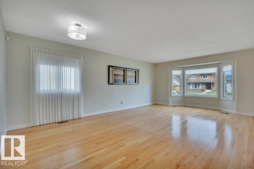 Spacious interior featuring wood-finish flooring, a contemporary semi-flush mount light fixture, and a large bay window - 18227 76 Avenue, Edmonton, AB - Indoor Photo Showing Living Room