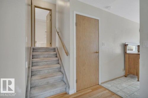 Carpeted staircase to the upper level with wood handrail and light wood-finish flooring - 18227 76 Avenue, Edmonton, AB - Indoor Photo Showing Other Room