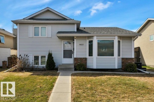 Split-level residence featuring light-colored siding, a dark shingled roof, a paved walkway, and a bay window detail - 18227 76 Avenue, Edmonton, AB - Outdoor