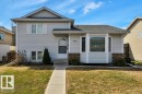 Split-level residence featuring light-colored siding, a dark shingled roof, a paved walkway, and a bay window detail - 18227 76 Avenue, Edmonton, AB  - Outdoor 