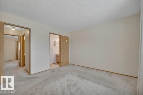 Carpeted room with neutral wall paint and wood-finish trim, featuring multiple doorways - 18227 76 Avenue, Edmonton, AB - Indoor Photo Showing Other Room