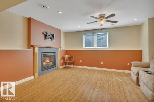 Open concept room featuring a built-in fireplace with a wood mantle and stone surround - 18227 76 Avenue, Edmonton, AB - Indoor Photo Showing Living Room With Fireplace