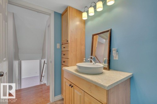 Vanity area featuring a vessel sink, light-toned wood cabinetry, a coordinating countertop, and a framed mirror - 18227 76 Avenue, Edmonton, AB - Indoor Photo Showing Bathroom